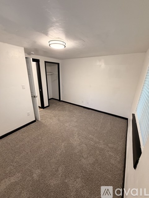 A carpeted room with a door and a window.