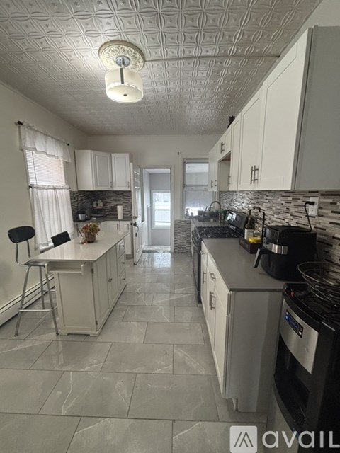 A kitchen with white cabinets and a tile floor.