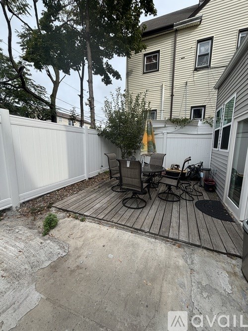 A patio with a table and chairs is surrounded by a white fence.