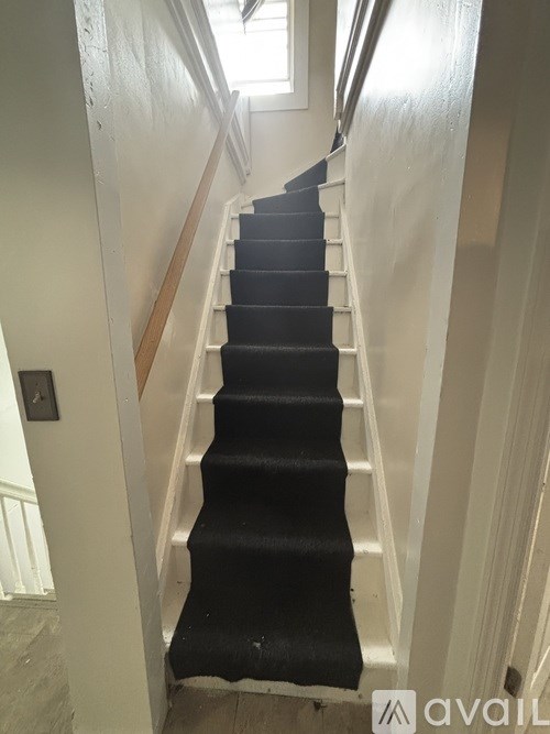 A staircase with black carpeted steps and white railings.