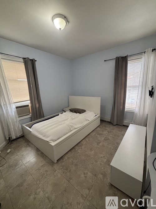 A bedroom with a large bed and a window with curtains.
