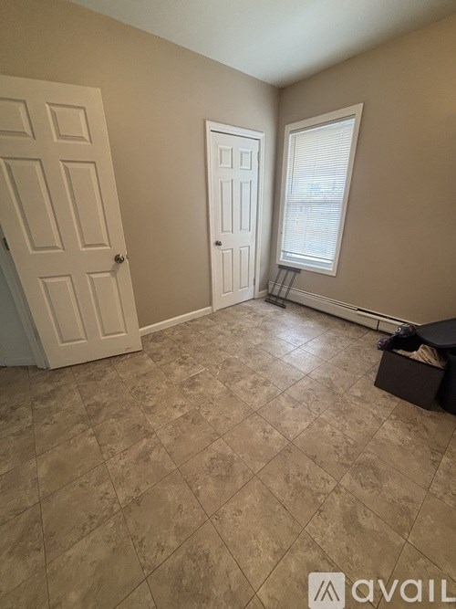 A room with a tiled floor and a window with blinds.
