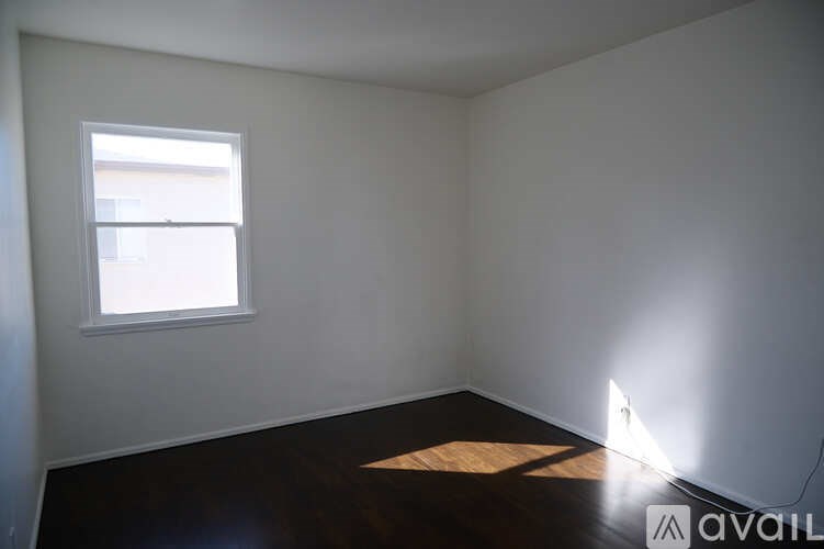 A room with a window and a wooden floor.
