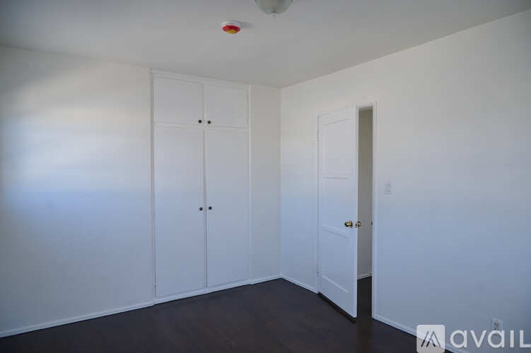 A room with a white door and a white cabinet with a red light on the ceiling.