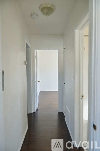 A long hallway with white walls and wood floors.