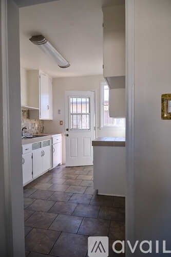 A kitchen with white cabinets and a tiled floor.