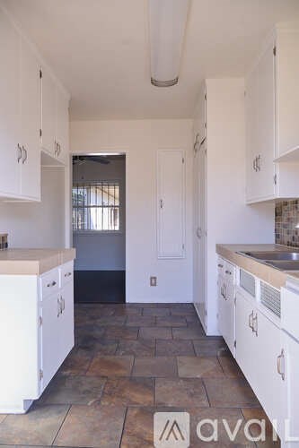 A kitchen with white cabinets and a stone floor.