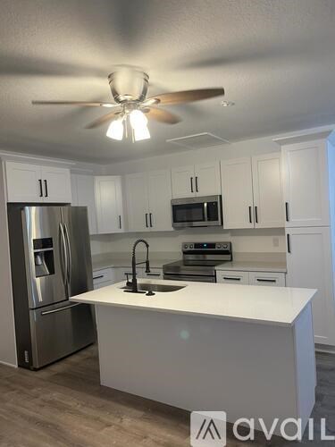 A kitchen with white cabinets and a stainless steel refrigerator.