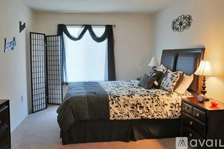 A bedroom with a large bed, a dresser, and a window with curtains.