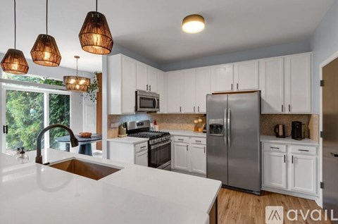 A kitchen with white cabinets and a stainless steel refrigerator.