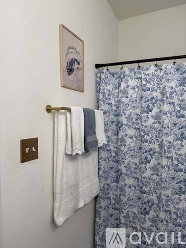A bathroom with a blue floral shower curtain and a white towel hanging on a towel rack.