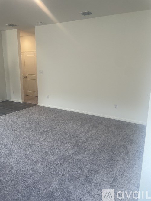 A room with a grey carpet and a wooden door.