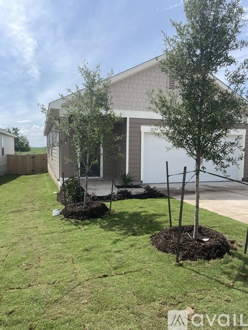 A house with a white garage door and a tree in front of it.