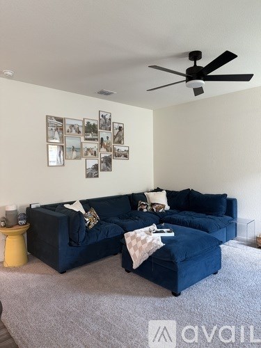 A living room with a blue couch and a ceiling fan.