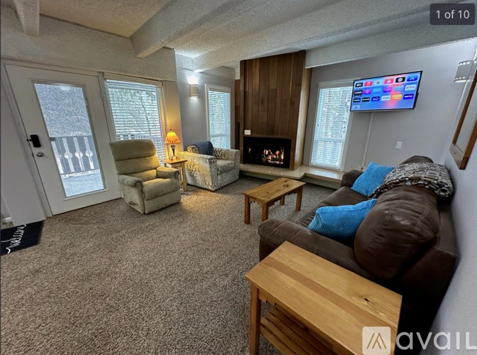 A living room with a brown couch, a wooden coffee table, and a flat-screen TV mounted on the wall.