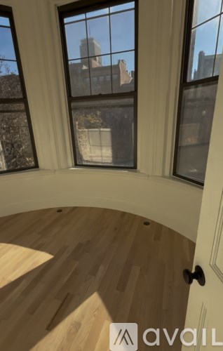 A room with a wooden floor and a large window overlooking a cityscape.