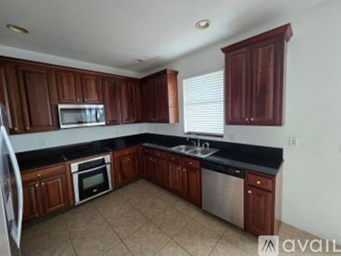 A kitchen with dark wood cabinets and black countertops.