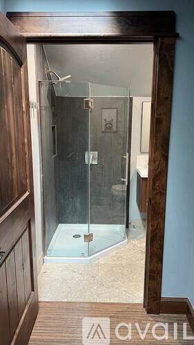 A bathroom with a glass shower door and a wooden cabinet.