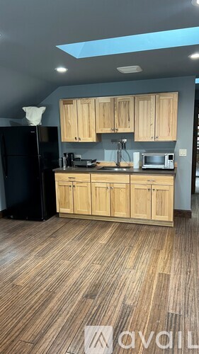 A kitchen with wooden cabinets and a black refrigerator.