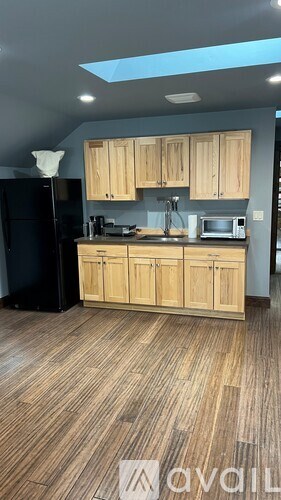 A kitchen with wooden cabinets and a black refrigerator.