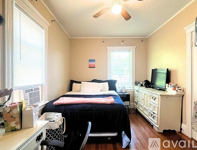 A bedroom with a bed, dresser, and window.