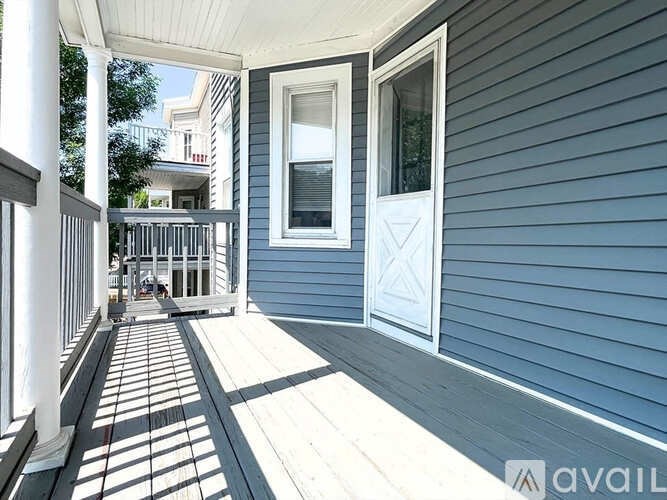A porch with a white railing and a white door.