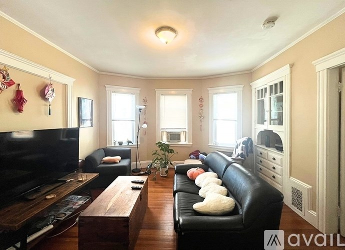 A living room with a black couch, a wooden coffee table, and a flat screen TV.