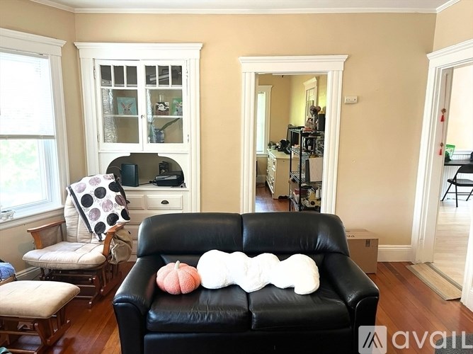 A black leather couch with a white pillow and a pumpkin on it.