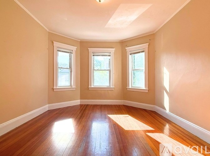 A room with wooden floors and three windows.