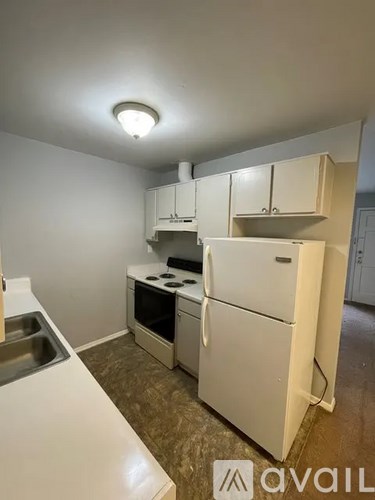 A small kitchen with a white fridge and a sink.