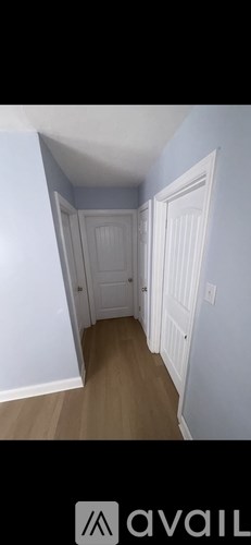 A hallway with a wooden floor and white walls.