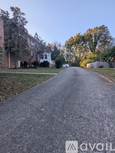 A street with a house on the left and trees on the right.
