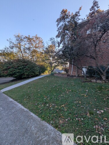 A grassy area with a sidewalk and a building in the background.