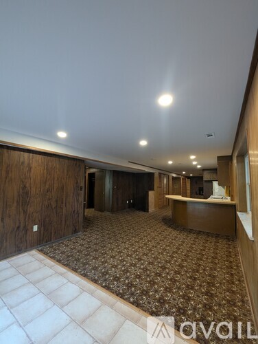 A spacious room with a patterned carpet and wooden walls.