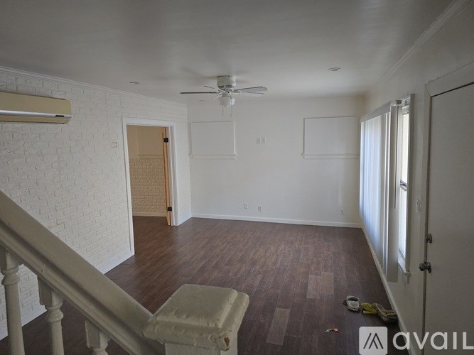 A room with a wooden floor and a staircase with a railing.