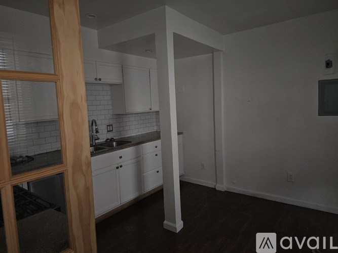 A kitchen with white cabinets and a wooden door frame.