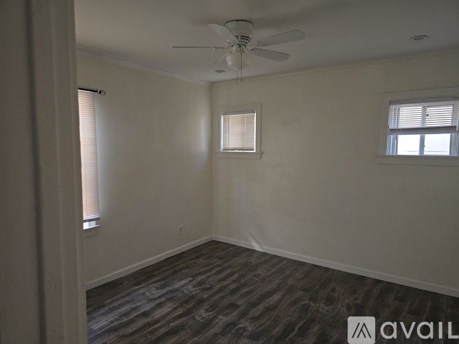 A room with a ceiling fan and two windows.