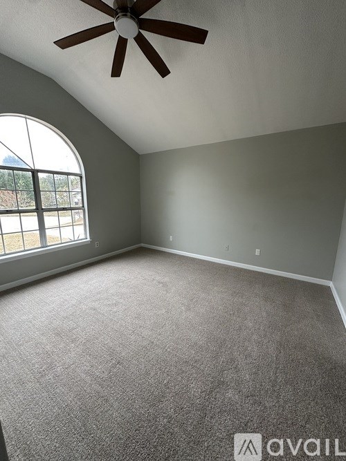 A room with a ceiling fan and a large window.