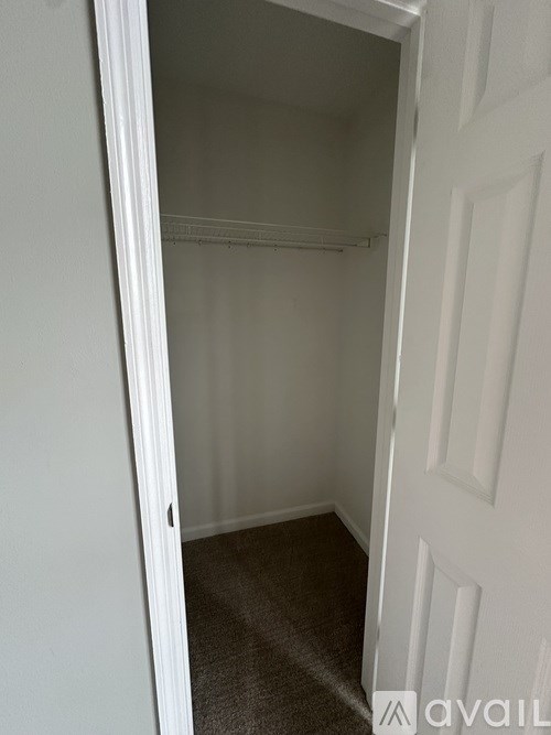 A white door with a small black handle is open to a carpeted hallway.