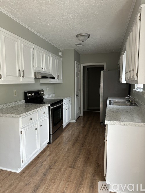 A kitchen with white cabinets and a marble countertop.