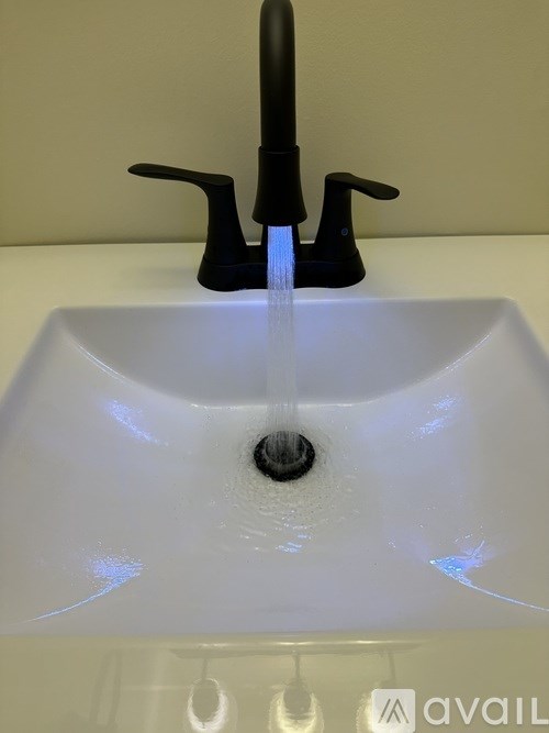 A black faucet with water flowing from it.