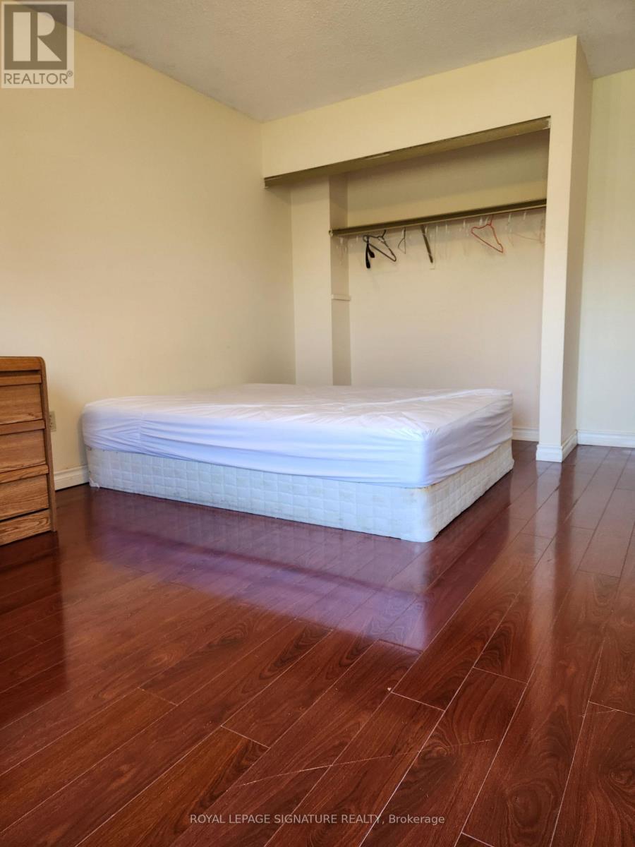 A bedroom with a bed, wooden floor and a white wall.