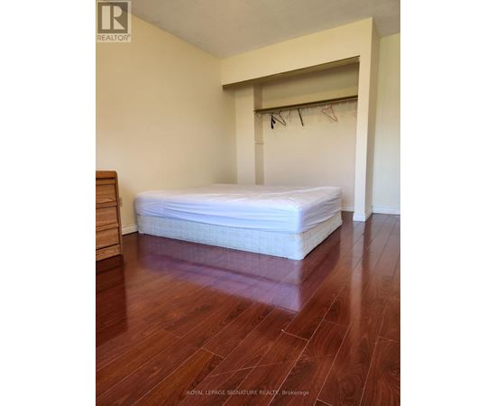 A bedroom with a bed, wooden floor and a white wall.