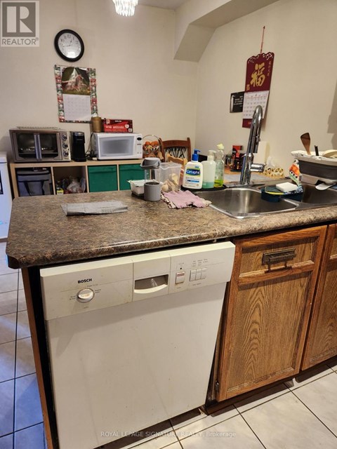 A kitchen with a white dishwasher and wooden cabinets.
