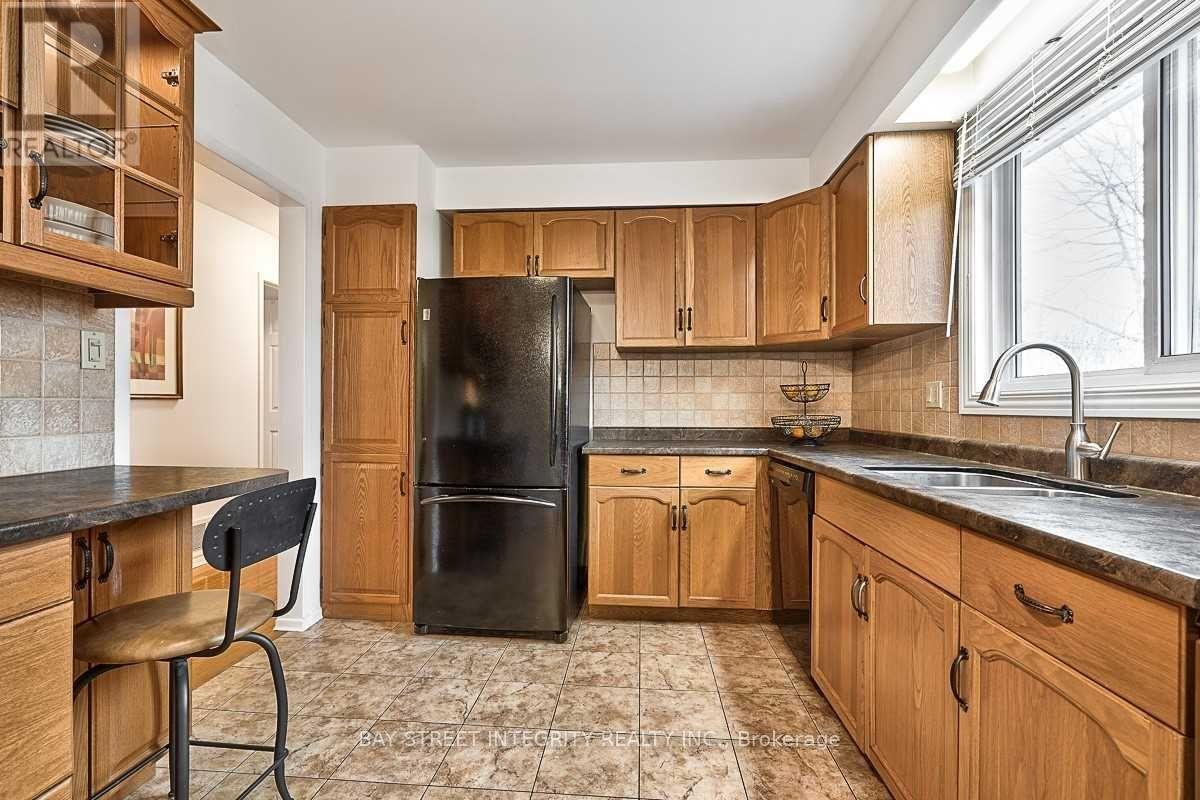 A kitchen with wooden cabinets and a black refrigerator.