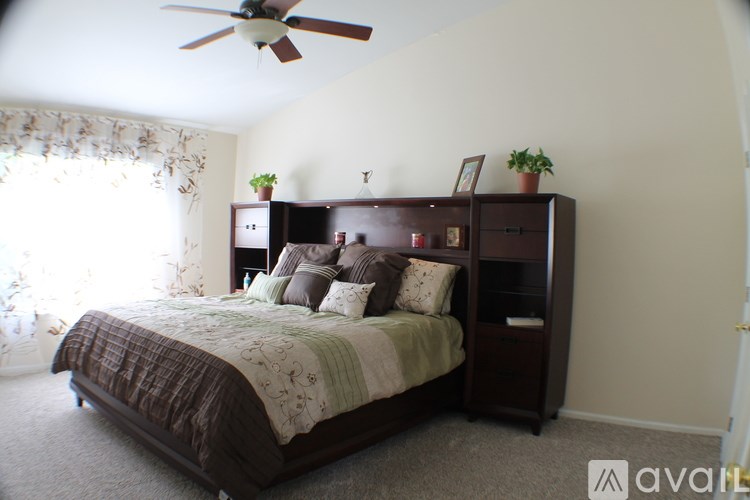 A bedroom with a bed, a ceiling fan, and a window with curtains.