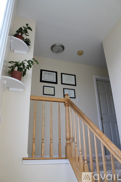 A staircase with a wooden banister and a framed certificate on the wall.