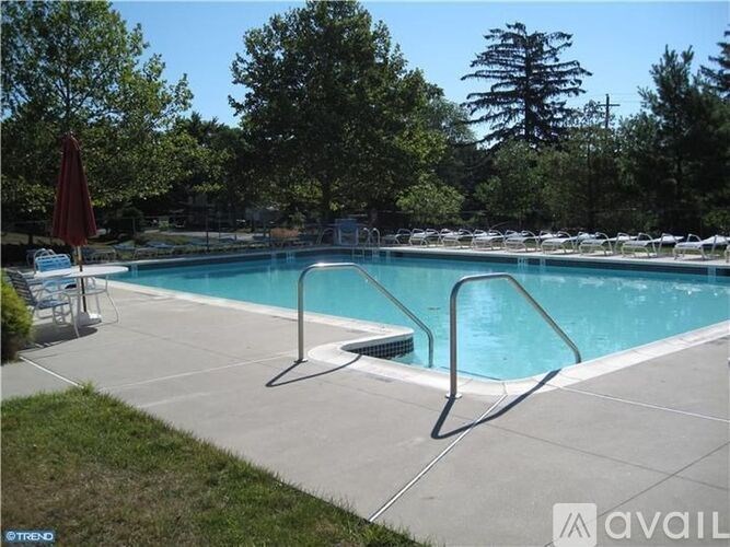 A pool with a red umbrella and chairs around it.