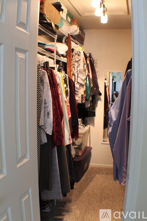 A white door is open to a hallway with clothes hanging on a rack.