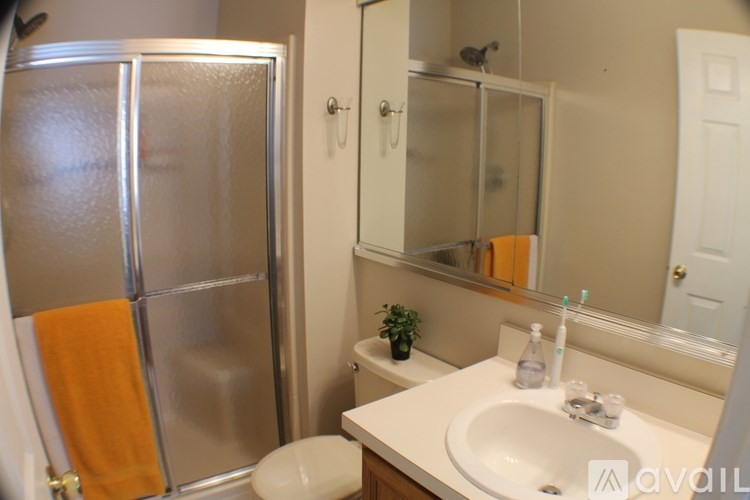 A bathroom with a sink, toilet, mirror, and a refrigerator.